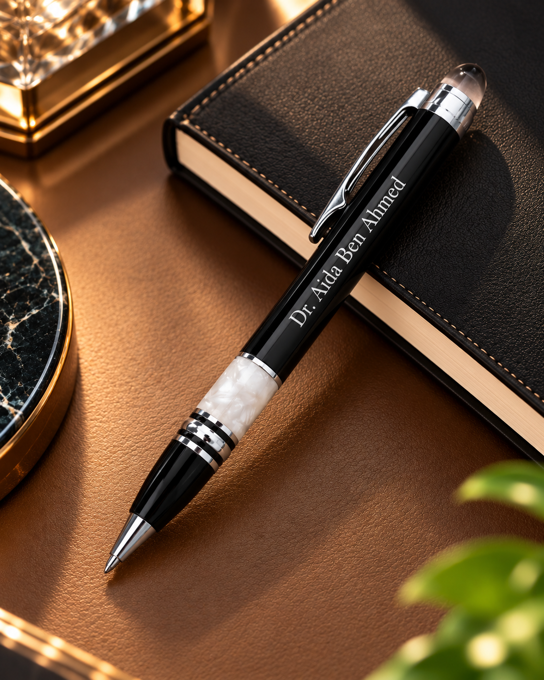 Stylo bille haut de gamme noir et nacre perle personnalisable posé sur un carnet noir
