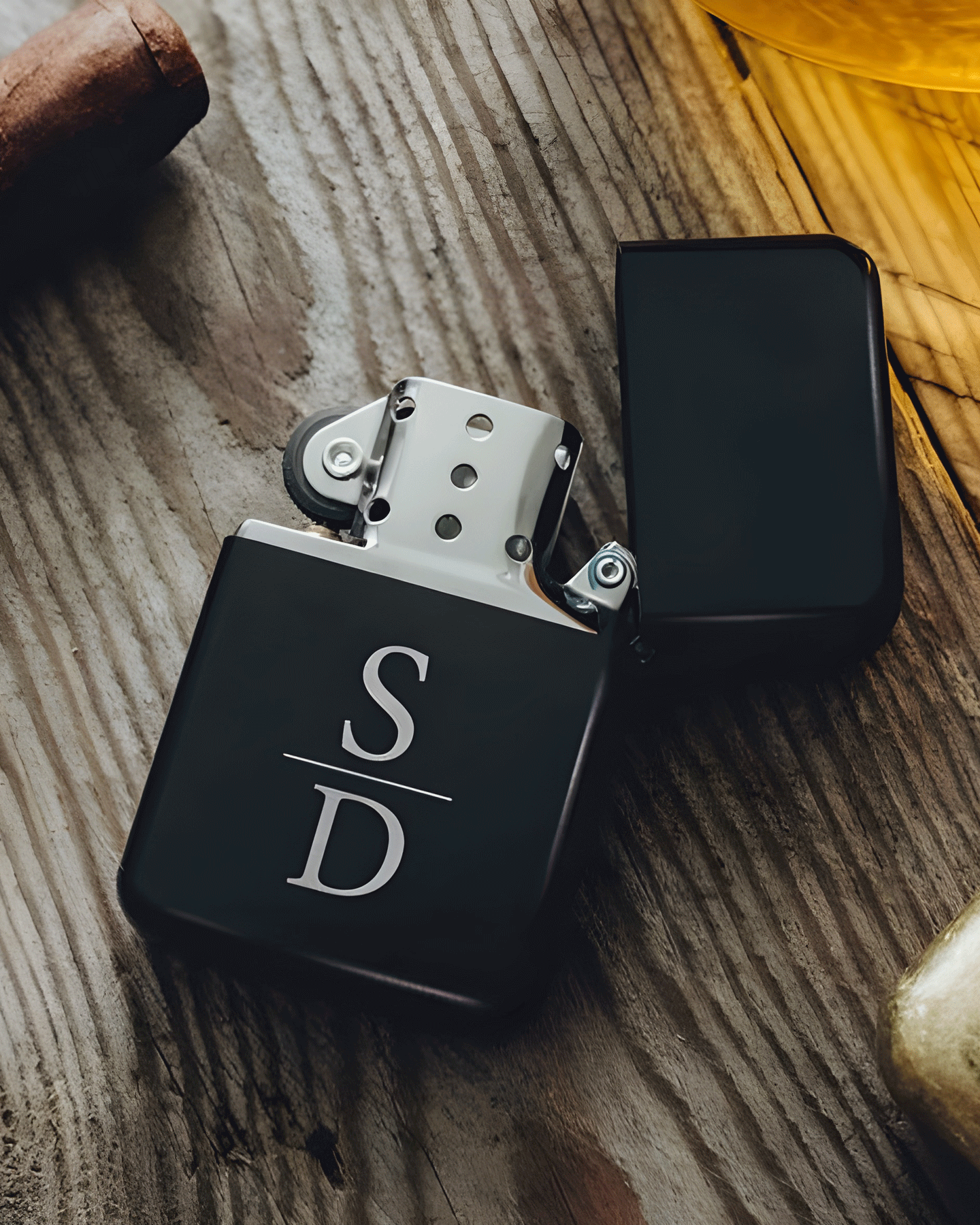 Elegant matte black flip-top lighter engraved with “S | D”, displayed open on a wooden surface. A refined accessory blending minimalist design with personal symbolism.